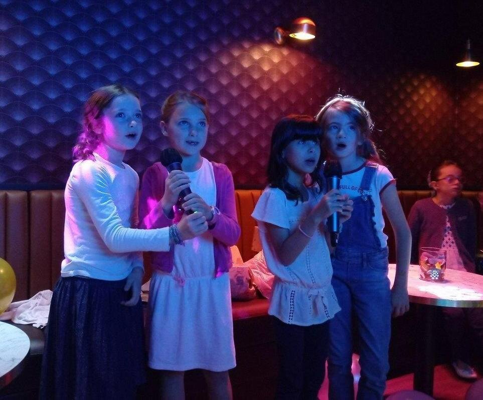 Un groupe de petites filles, micro en main qui chantent lors d’une session Musikall kids, anniversaire enfant à Reims.